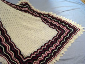My hap shawl with a simple pattern in the center and randomly striped border in the feather and fan pattern, with a simple pointed edging.