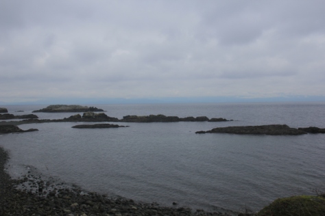 Grey rocks upon grey seas in front of grey skies.