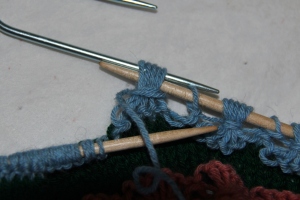 Slip tip of right hand needle through the sts on the cable hook.